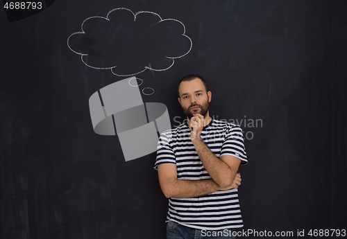 Image of young future father thinking in front of black chalkboard