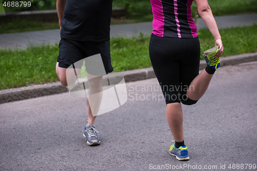 Image of runners team warming up and stretching before morning training