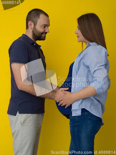 Image of pregnant couple  isolated over yellow background