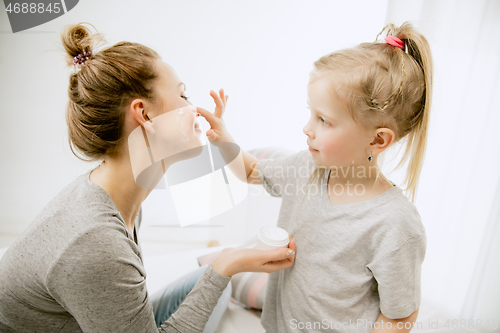 Image of Young mother and her little daughter hugging and kissing on bed