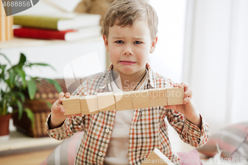 Image of Little child sitting on the floor. Pretty boy palying with wooden cubes at home