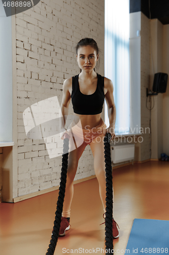 Image of Woman with battle ropes exercise in the fitness gym.