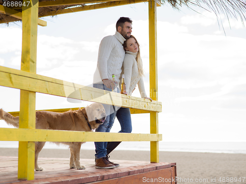 Image of young couple drinking beer together at the beach