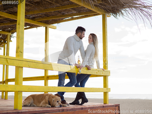 Image of young couple drinking beer together at the beach