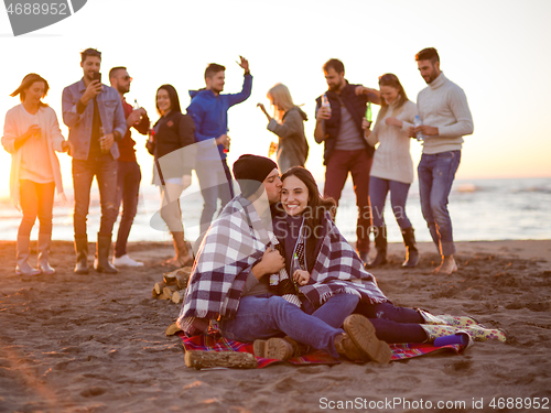 Image of Couple enjoying with friends at sunset on the beach