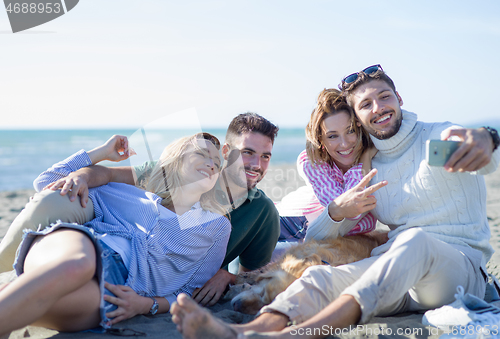 Image of Group of friends having fun on beach during autumn day