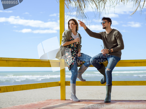 Image of young couple drinking beer together at the beach