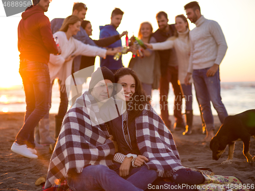 Image of Couple enjoying with friends at sunset on the beach