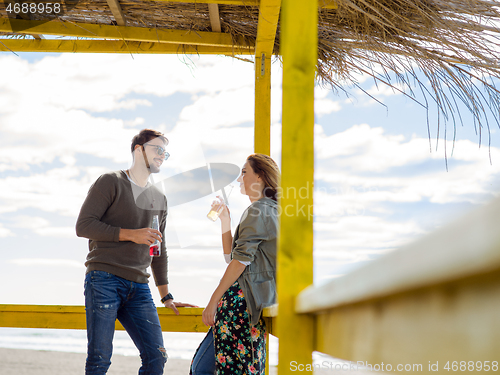 Image of young couple drinking beer together at the beach