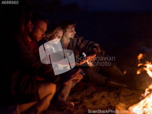 Image of Couple enjoying with friends at night on the beach