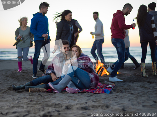 Image of Couple enjoying with friends at sunset on the beach