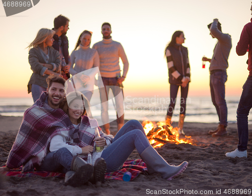 Image of Couple enjoying with friends at sunset on the beach