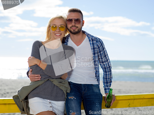 Image of young couple drinking beer together at the beach