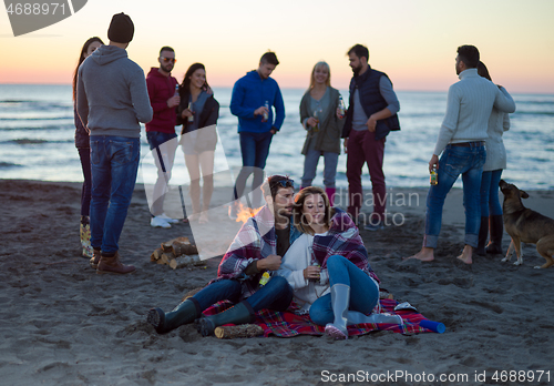 Image of Couple enjoying with friends at sunset on the beach