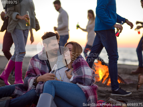 Image of Couple enjoying with friends at sunset on the beach