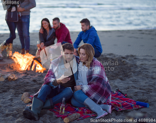 Image of Couple enjoying bonfire with friends on beach