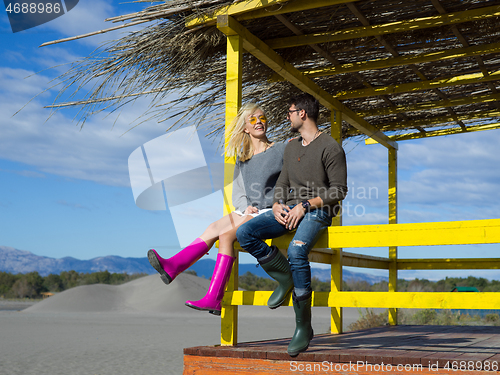 Image of young couple drinking beer together at the beach