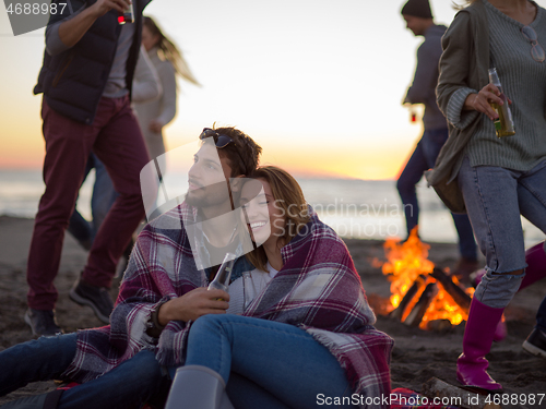 Image of Couple enjoying with friends at sunset on the beach