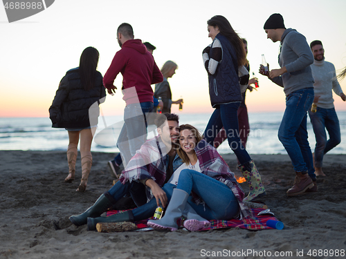 Image of Couple enjoying with friends at sunset on the beach