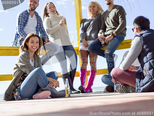 Image of Group of friends having fun on autumn day at beach