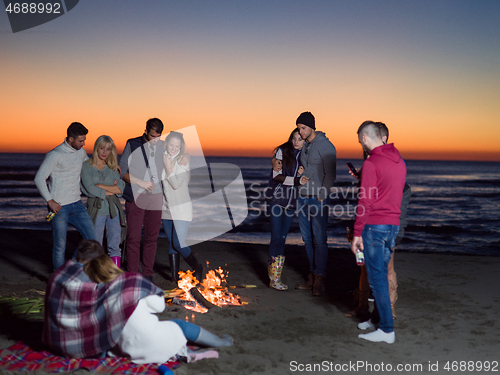 Image of Friends having fun at beach on autumn day