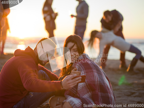 Image of Couple enjoying bonfire with friends on beach