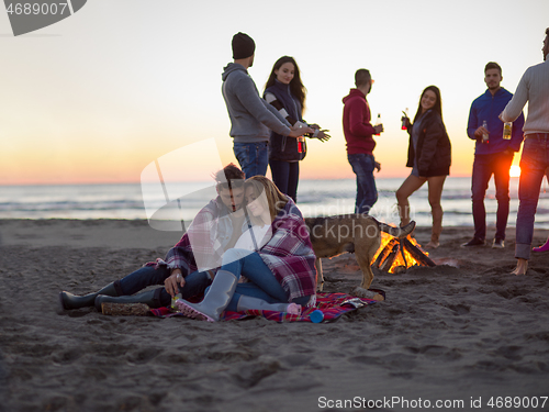 Image of Couple enjoying with friends at sunset on the beach