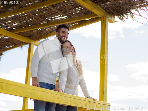 Image of young couple drinking beer together at the beach