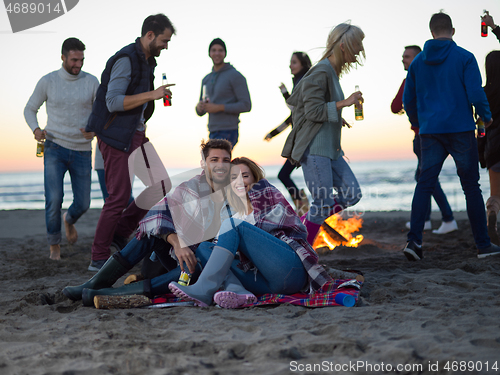 Image of Couple enjoying with friends at sunset on the beach