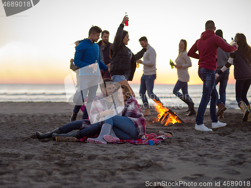 Image of Couple enjoying with friends at sunset on the beach