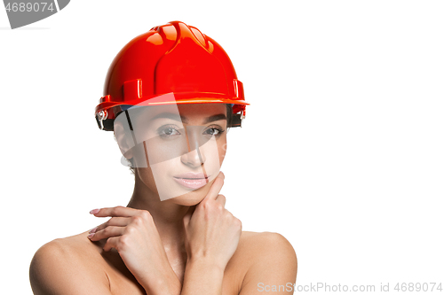 Image of Portrait of confident female worker in orange helmet