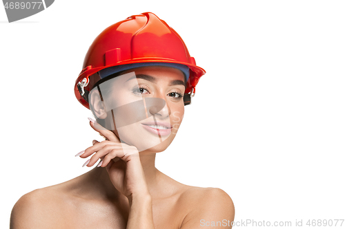 Image of Portrait of confident female worker in orange helmet