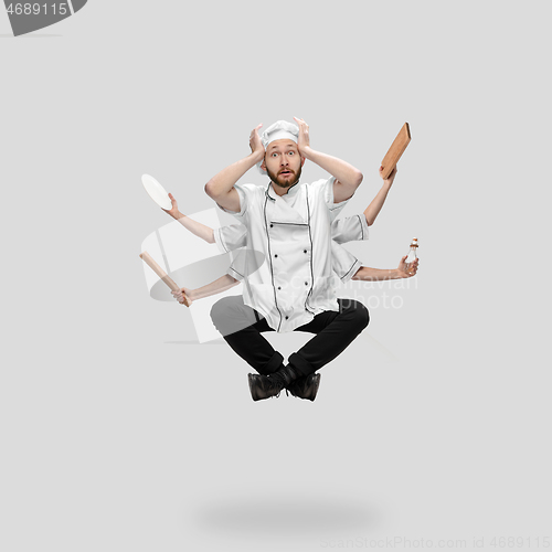 Image of Cooker, chef, baker in uniform multitask like shiva isolated on gray studio background