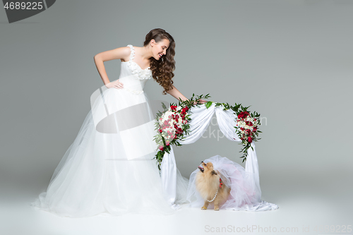 Image of bride girl with dog bride under flower arch