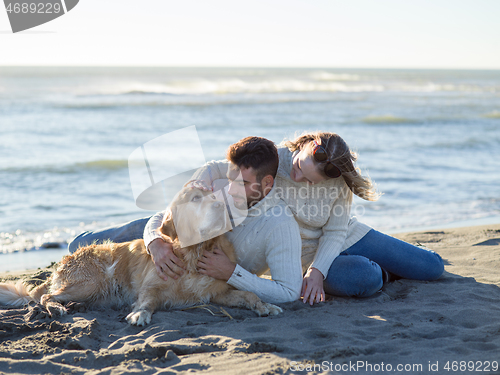 Image of Couple with dog enjoying time on beach