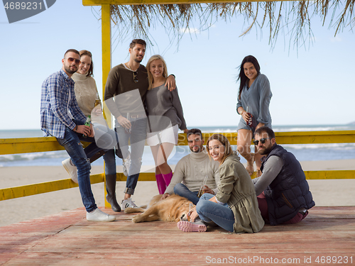 Image of Group of friends having fun on autumn day at beach