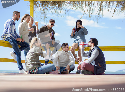 Image of Group of friends having fun on autumn day at beach