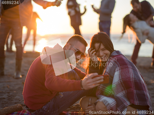 Image of Couple enjoying bonfire with friends on beach