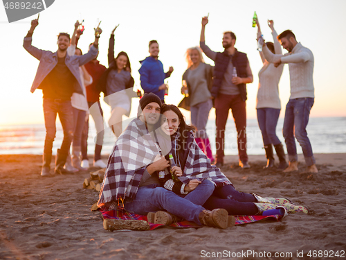 Image of Couple enjoying with friends at sunset on the beach