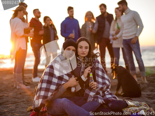 Image of Couple enjoying with friends at sunset on the beach