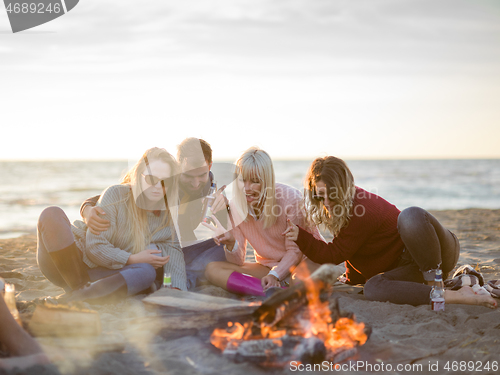 Image of Friends having fun at beach on autumn day