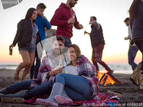 Image of Couple enjoying with friends at sunset on the beach