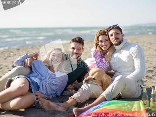 Image of Group of friends having fun on beach during autumn day