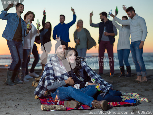 Image of Couple enjoying with friends at sunset on the beach