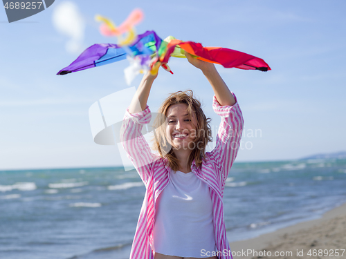 Image of Young Woman holding kite at beach on autumn day