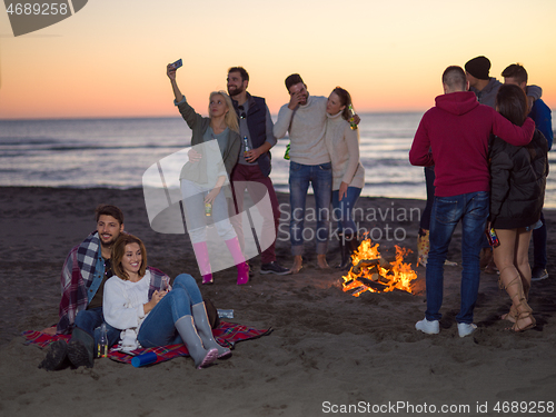 Image of Couple enjoying with friends at sunset on the beach