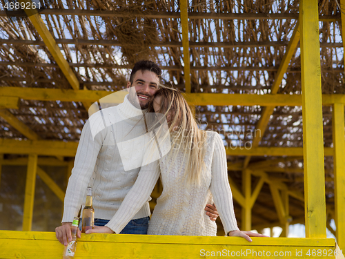 Image of young couple drinking beer together at the beach