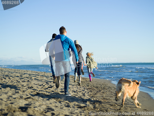 Image of Group of friends running on beach during autumn day