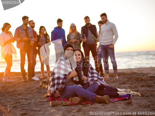 Image of Couple enjoying with friends at sunset on the beach