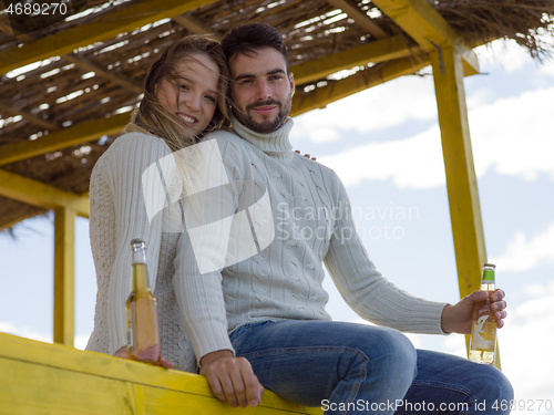 Image of young couple drinking beer together at the beach